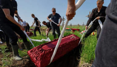 People take part in a funeral ceremony to bury the remains of sixty service members of the Russian armed forces and three civilians.