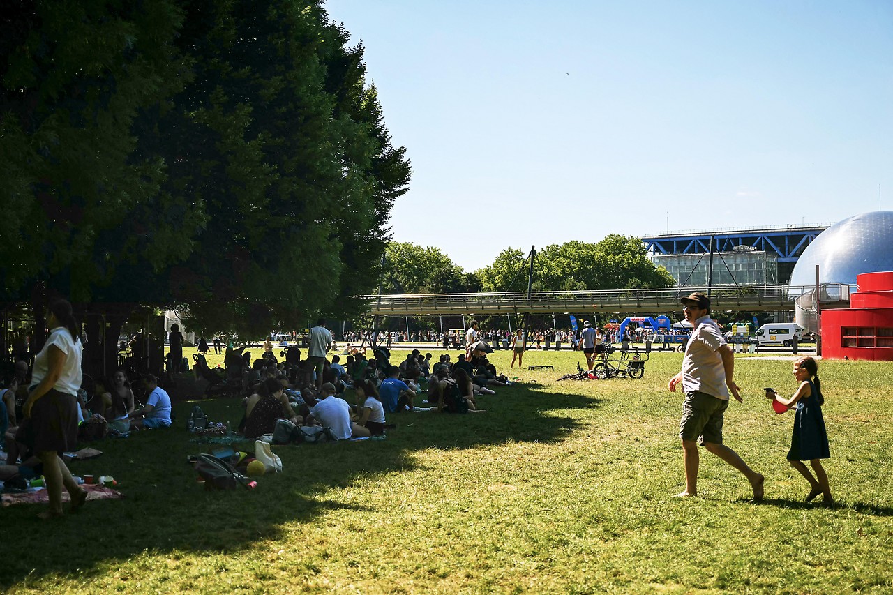 Menschen sitzen im PArk „La Villette“ in Paris im Schatten
