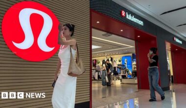 A woman in a white dress walks past a Lululemon store with its signature red logo displayed prominently on the wall, as shoppers browse inside the store, on 4 June, 2025 in Chongqing, China.