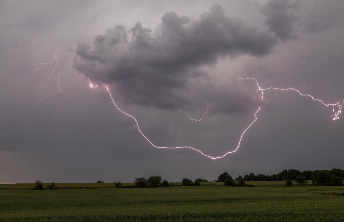 Der Blitz eines Gewitters ist am Nachmittag über einem Feld bei Oberursel-Oberstedten zu sehen