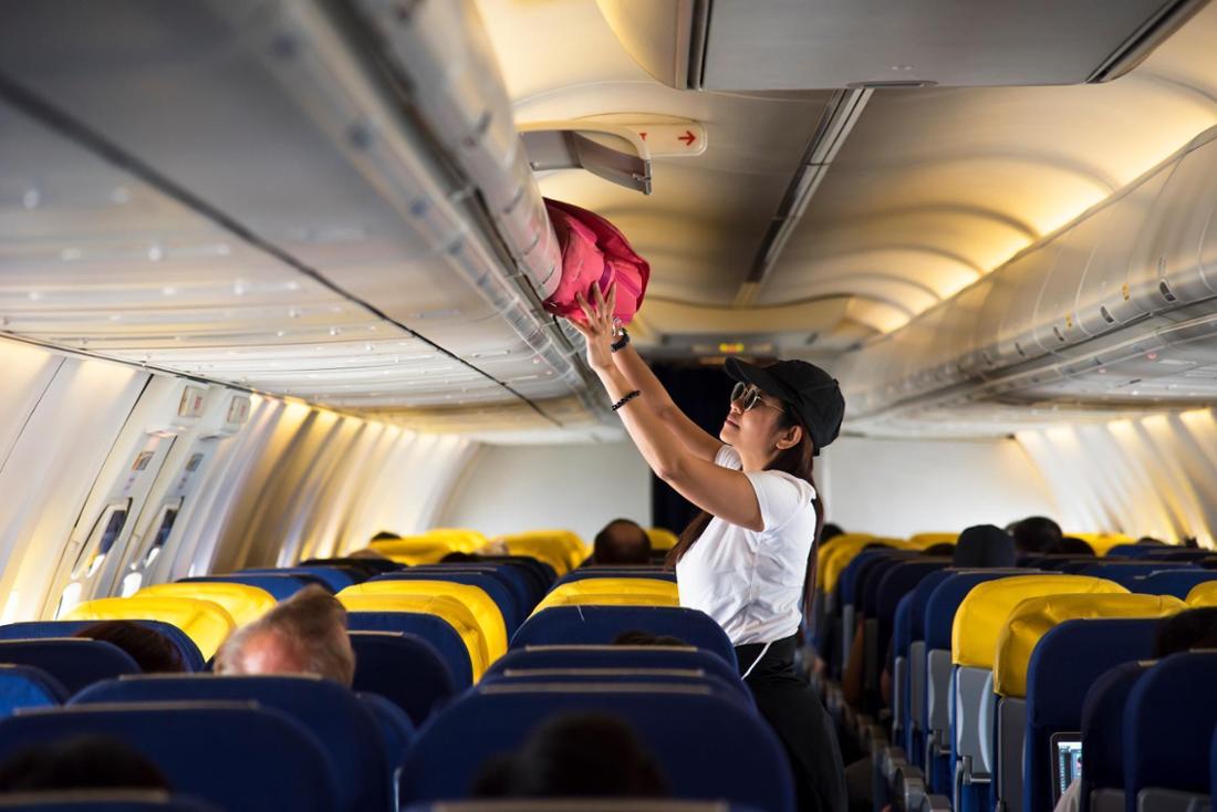 Eine junge Frau verstaut ihr Handgepäck im Flugzeug.
