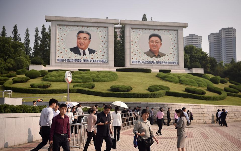 People walk in front of huge portraits of late North Korean leaders Kim Il Sung and Kim Jong Il in Pyongyang in May