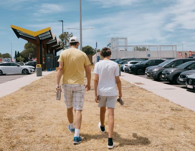 People pause to cool off and hydrate at the Ambrussum motorway rest area, between Montpellier and Nîmes, on June 27, 2025.