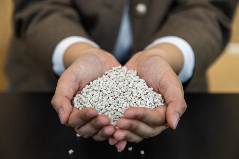  Light-colored plastic pellets held in cupped hands.