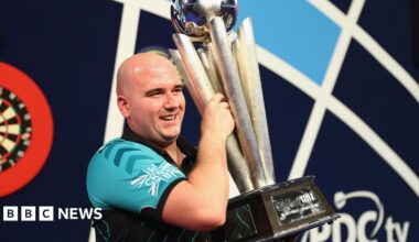 Rob Cross holding the world darts championship trophy.