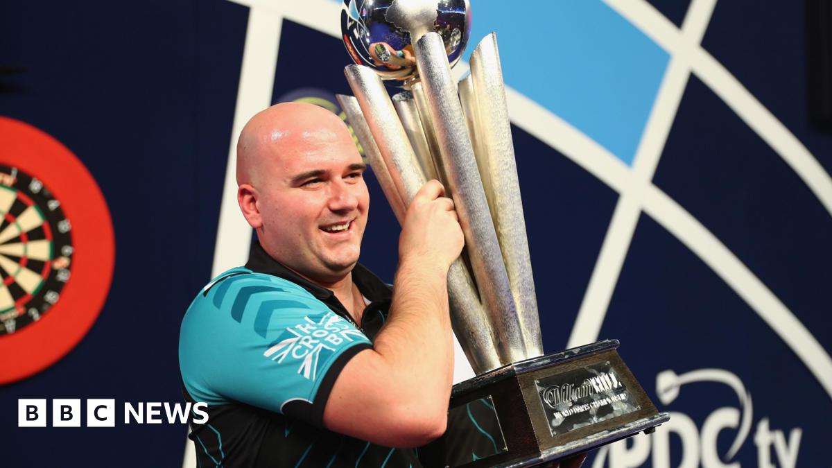 Rob Cross holding the world darts championship trophy.