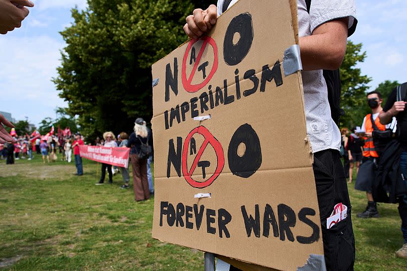 A man holds a placard during a demonstration ahead of the NATO summit in The Hague, Netherlands, Sunday, June 22, 2025. 