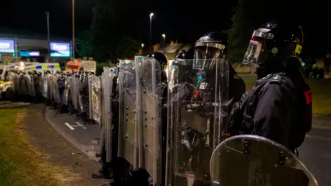PA Media A line of police in riot gear. Their faces are covered.
