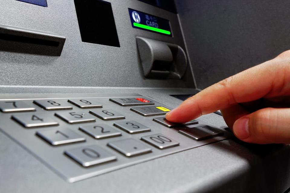 A stock photo shows a person using an ATM.
