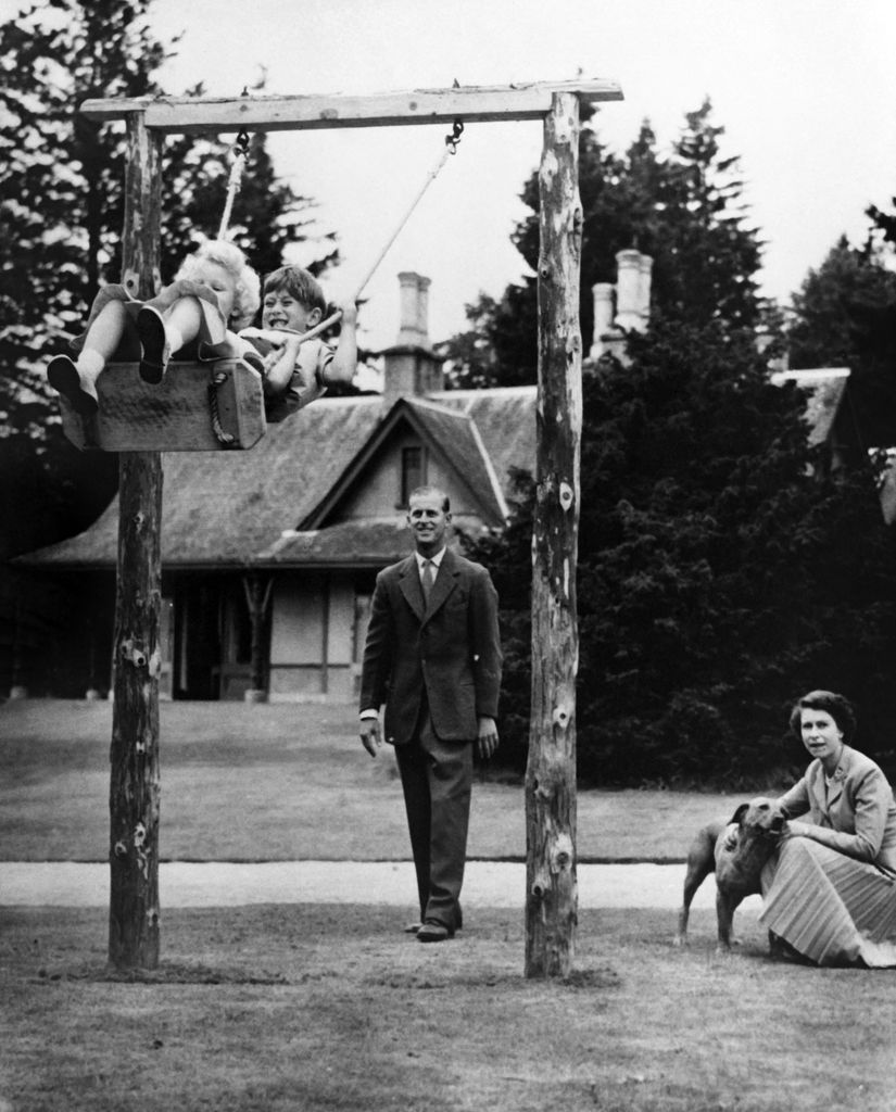Prince Charles and Princess Anne being pushed on a swing by their father, the Duke of Edinburgh, in Balmoral