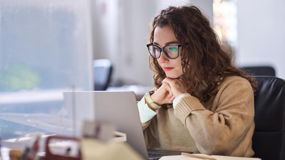 Young serious professional woman using laptop