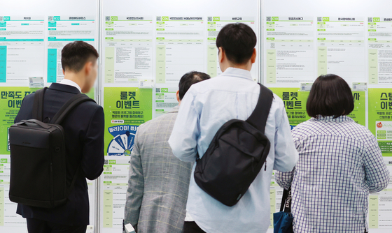 Jobseekers look at notices at a job fair held on June 5 in Coex, southern Seoul. [YONHAP]