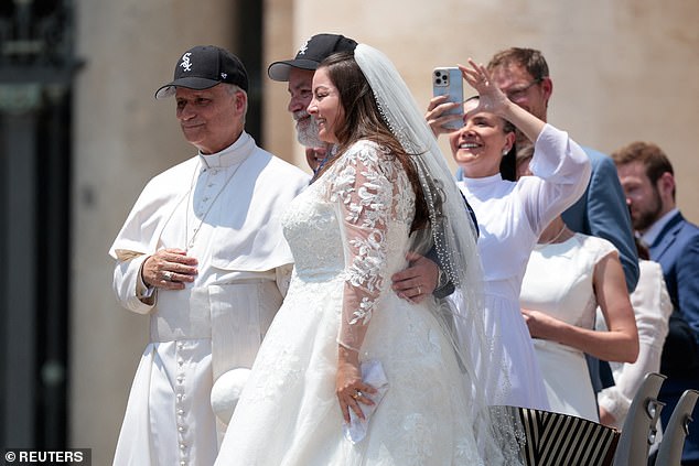 Pope Leo XIV wears a Chicago White Sox cap as he poses for a picture with a bride and groom