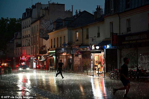 FRANCE: People run for shelter on a street in the 20th Arrondissement during a thunderstorm, in Paris, on June 25