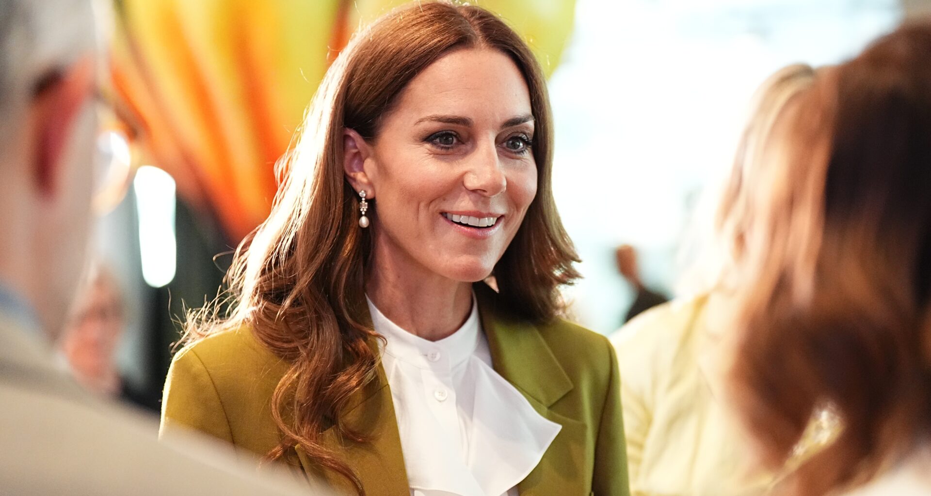 Catherine, Princess of Wales smiles, wearing an olive green suit, at the British Fashion Council at 180 Studios in central London