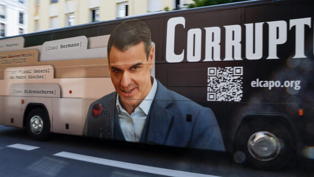 A bus with an image of Spain's prime minister, Pedro Sánchez, with the word "Corrupt" drives by his party headquarters shortly before he was scheduled to hold a press conference on June 12, 2025.