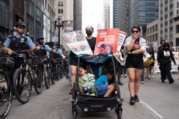 Santi Brito-Lucero, 4, and Remy Brito-Lucero, 7, sleep as hundreds march down Michigan Avenue towards Trump Tower while protesting nationwide immigration raids by federal law enforcement and ICE on June 12, 2025, in Chicago. (Audrey Richardson/Chicago Tribune)