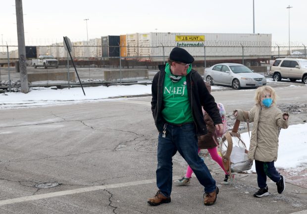 Anthony Moser and daughters Lucy, 10, and Sofia, 8, walk to school past an Intermodal Facility along Pershing Road and St. Louis Avenue in Chicago on Feb. 14, 2025. Moser is an activist who is the board president of Neighbors for Environmental Justice or N4EJ, a grassroots nonprofit on the Southwest Side. (Antonio Perez/Chicago Tribune)