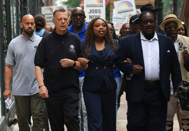 The Rev. Michael Pfleger, front left, the Rev. Ciera Bates-Chamberlain, center, and the Rev. Marshall Hatch lock arms as they march outside a Target store at 1 S. State St. to protest the company's policy to scale back workforce diversity June 12, 2025, in Chicago. (John J. Kim/Chicago Tribune)