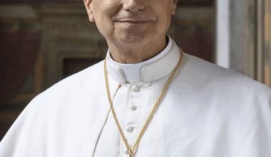 Pope Leo XIV smiles in a newly released photograph, wearing the traditional white cassock and gold pectoral cross first seen during his May 8 election greeting at St. Peter’s Basilica (Holy See Press Office).