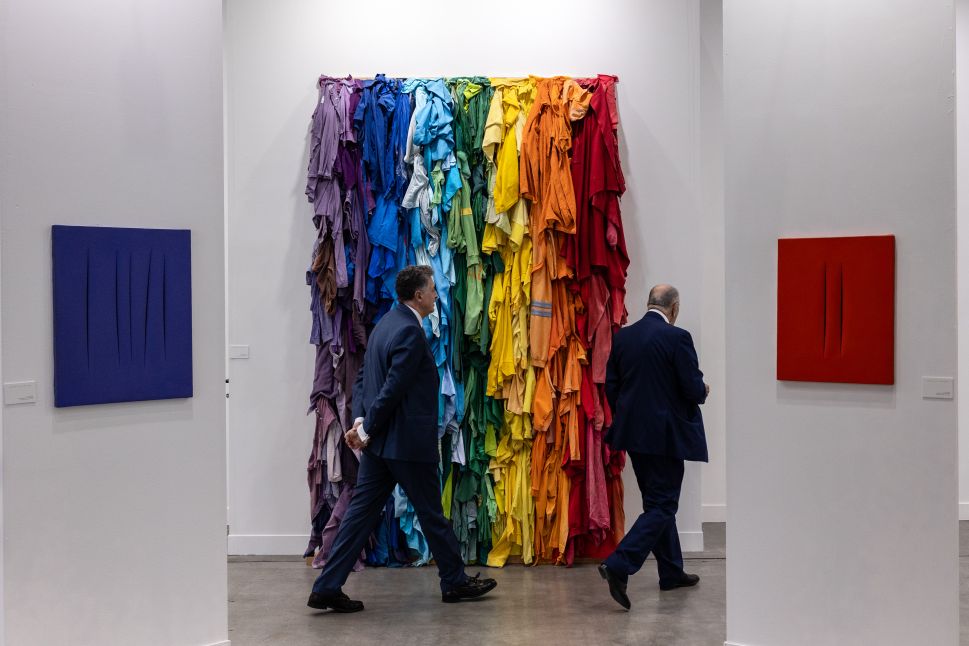 Two men walk past artworks by Italian artists Michelangelo Pistoletto ("Stracci della Pace") and Lucio Fontana during Miart - the international modern and contemporary art fair presenting the widest offer in Italy - on April 11, 2024 in Milan, Italy. 