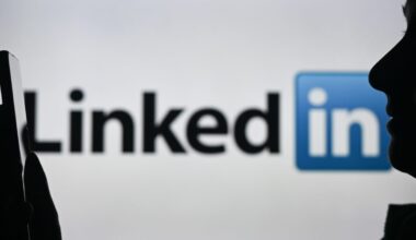 An image of a woman holding a cell phone in front of a LinkedIn logo displayed on a computer screen.