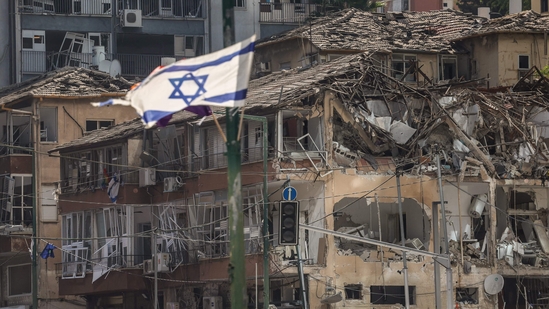Iran Israel war live updates:  The Israeli flag flutters in front of a destroyed building at the site of an Iranian missile attack in Ramat Gan in central Israel near Tel Aviv.