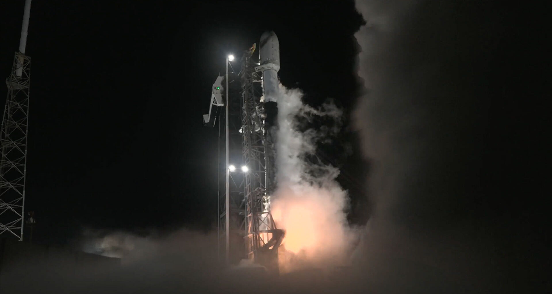 a white and black rocket lifts off into the night sky.