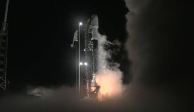 a white and black rocket lifts off into the night sky.