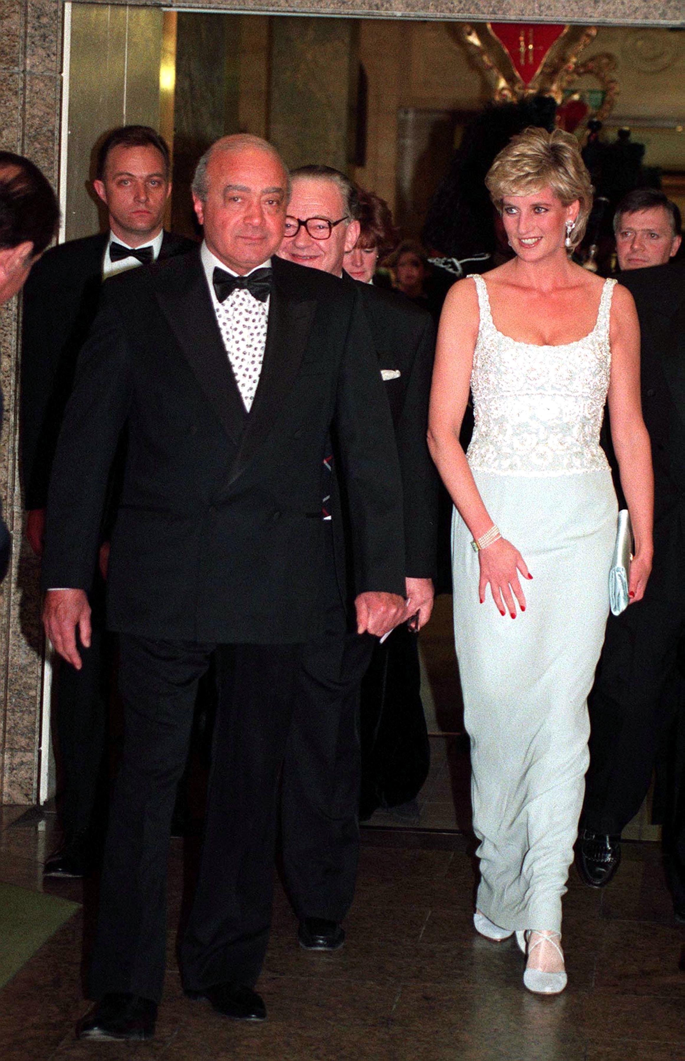 Mohamed Al-Fayed in a tux walking next to Princess Diana wearing a white gown