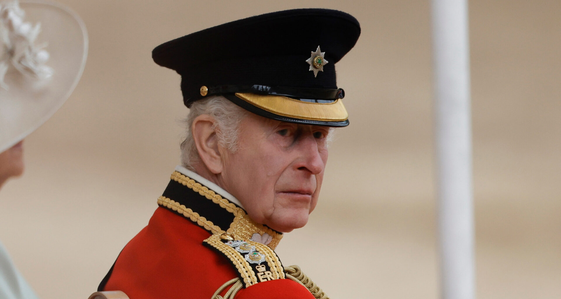 King Charles wears red military uniform and a black hat at Trooping the Colour