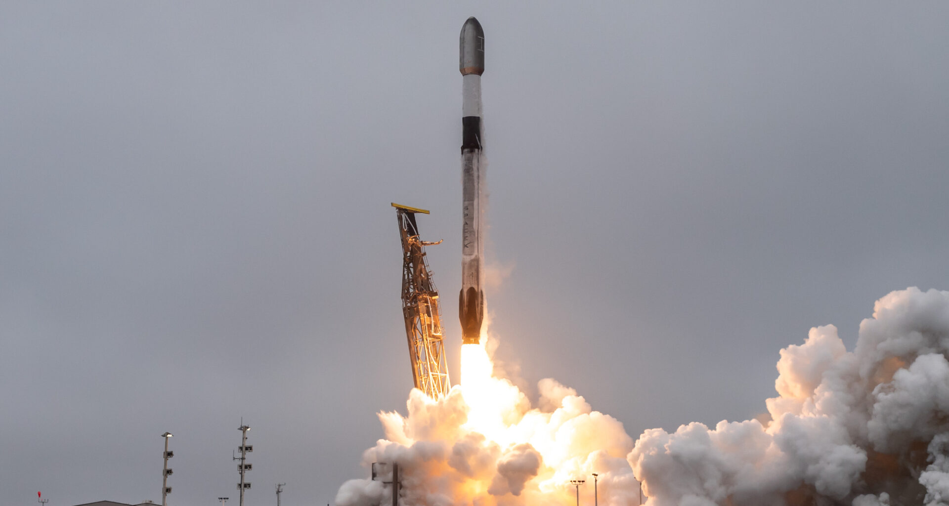 a black and white rocket launches into a cloudy sky