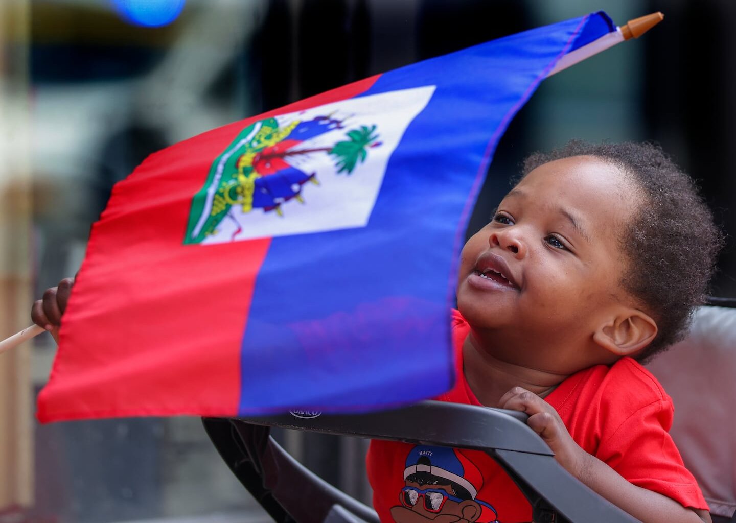 Ozzie Milfort, then 19-months, waved his flag at the start of the Haitian Flag Day parade last month in Mattapan Square.