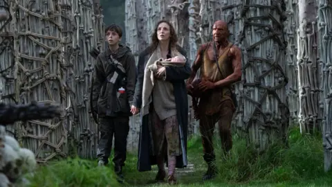 Sony Pictures Spike, Jodie Comer holding a newborn, and Ralph Fiennes as Dr Kelson 