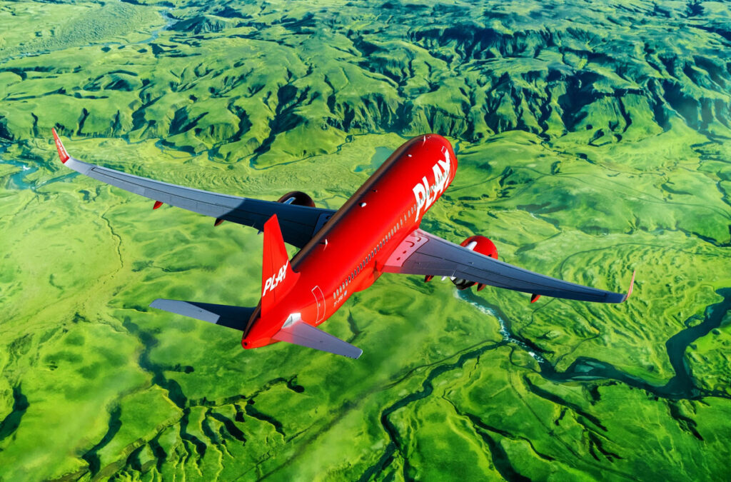 A PLAY Airlines aircraft in flight over green terrain