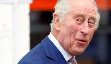 King Charles laughs while wearing a navy suit