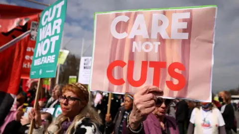 EPA A crowd of protestors holding placards protesting against welfare cuts.