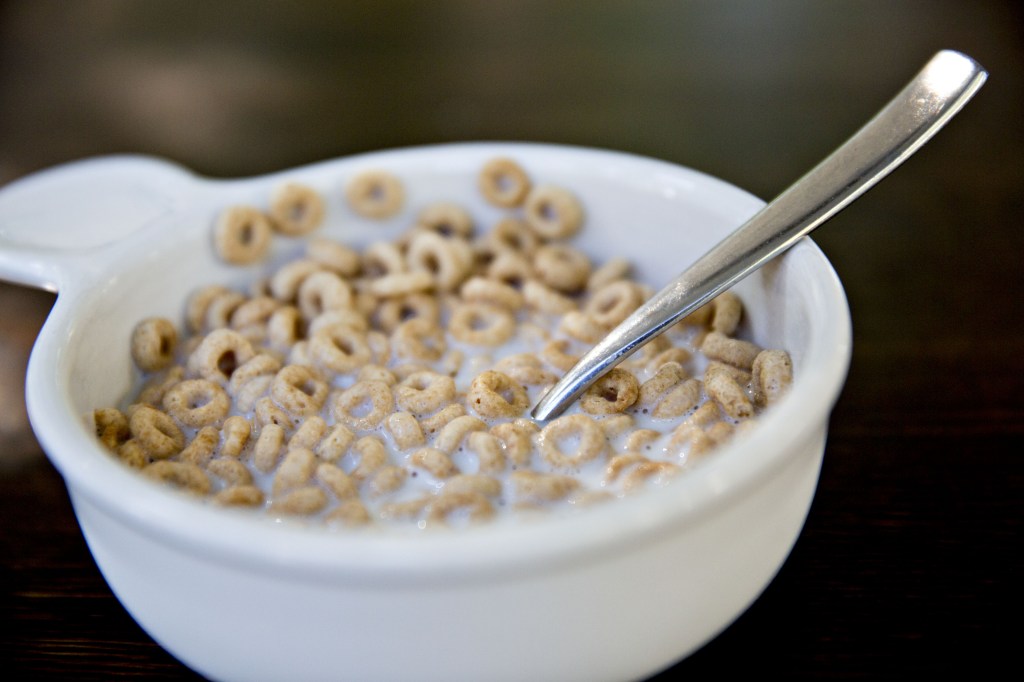 Bowl of Cheerios cereal with milk and a spoon.