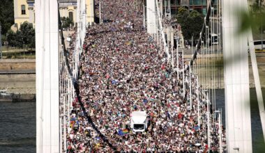 Blick auf eine große Brücke in Budapest, die mit Menschen überfüllt ist. Auch die Straße hinter der Brücke ist voller Menschen.