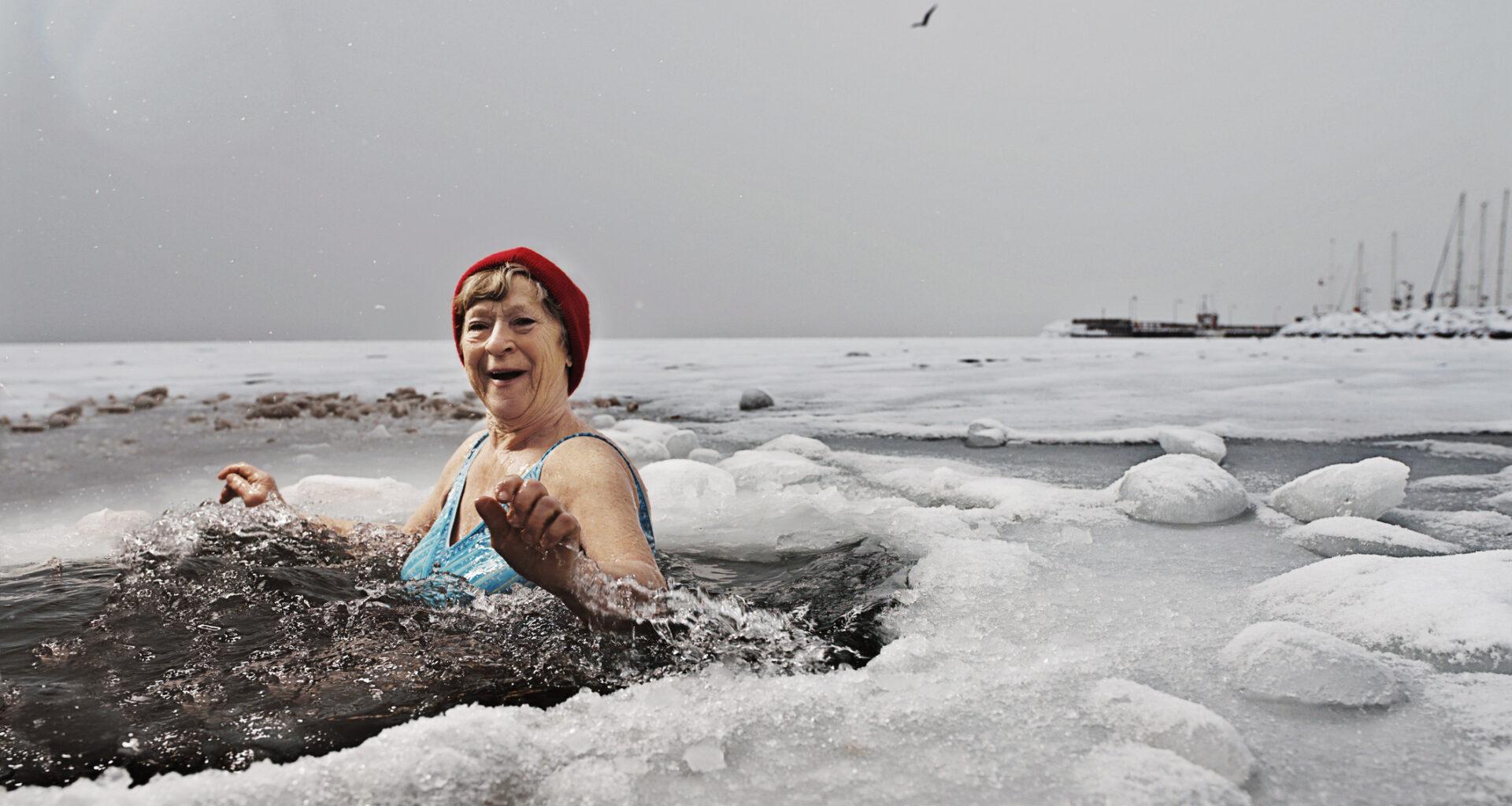 A woman bathes in a hole in the ice on a frozen sea.