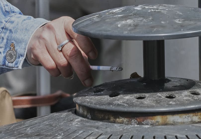 A woman taps the ash from a cigarette into an ashtray at Gare du Nord train station in Paris, Thursday, May 29 2025.