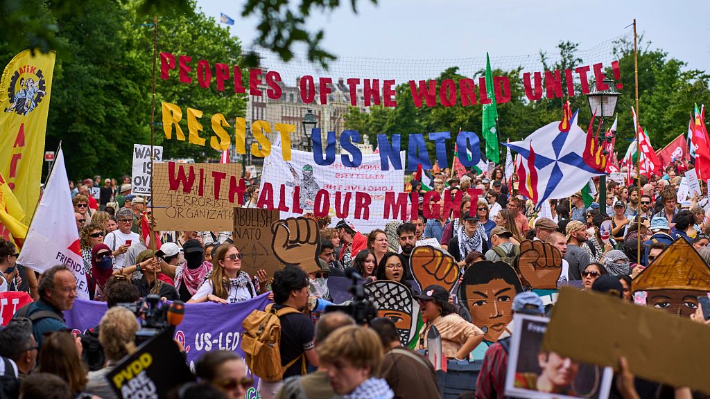 A woman holds a placard during a demonstration ahead of the NATO summit in The Hague, Netherlands, Sunday, June 22, 2025.