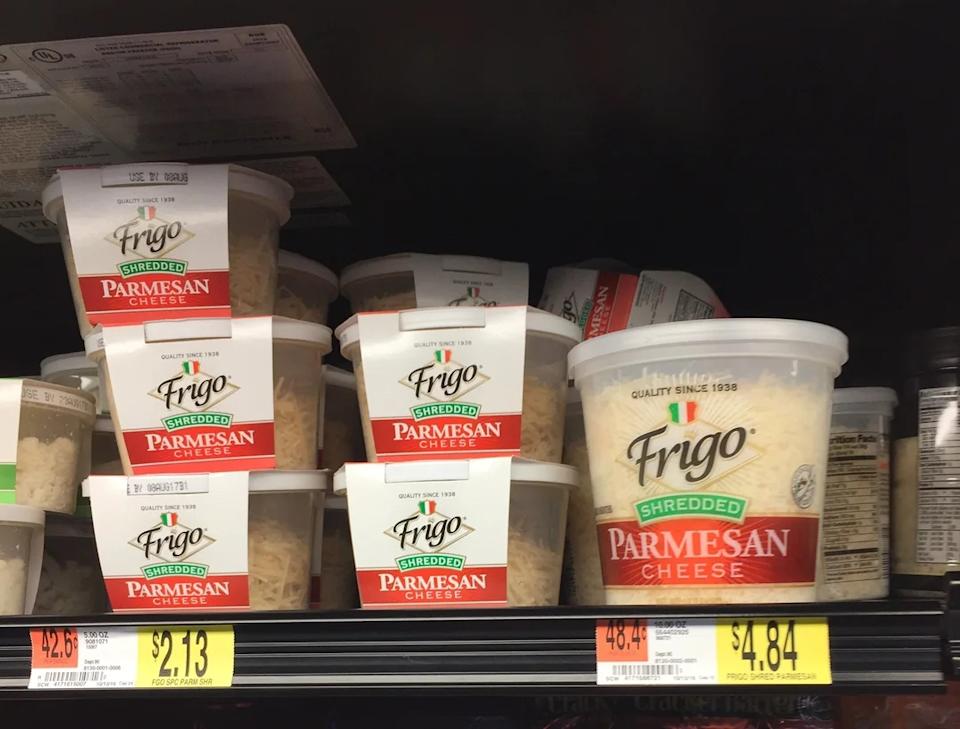 Parmesan cheese containers on a grocery shelf with price tags, the smaller one is priced 42.6 cents per ounce and the larger container is at 48.4 cents per ounce