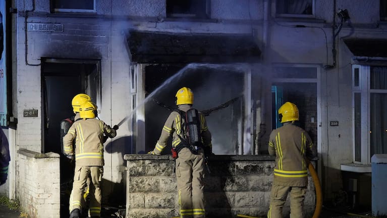 Emergency services work outside a house in Ballymena, Northern Ireland, as people protest over an alleged sexual assault in the Co Antrim town.