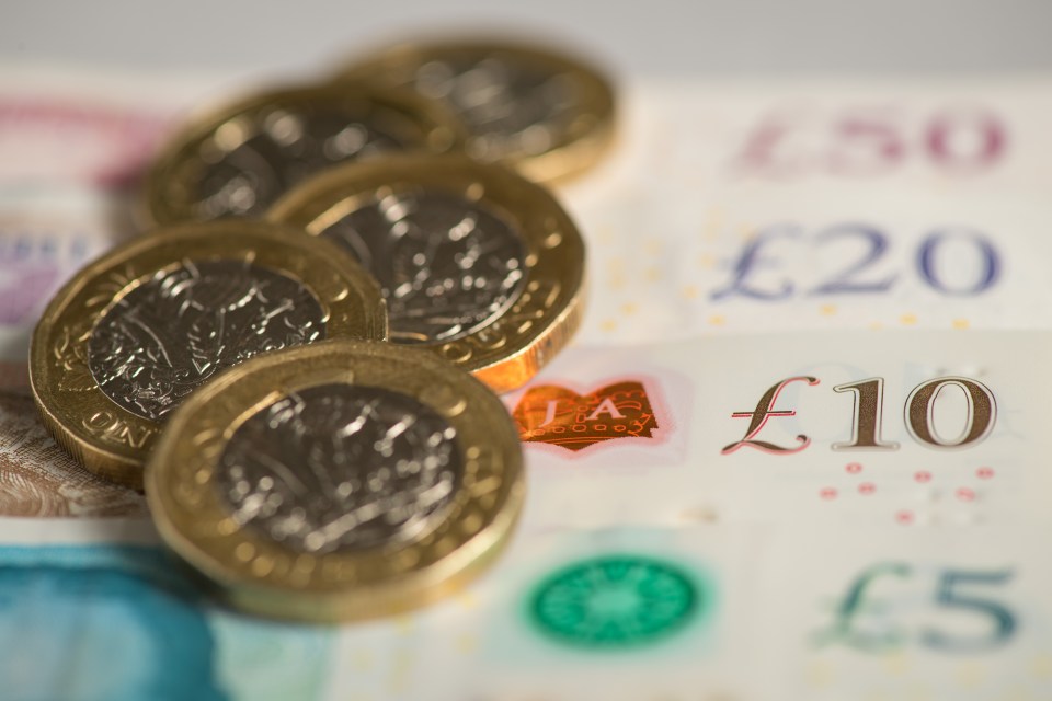 Close-up of British one-pound coins on banknotes.