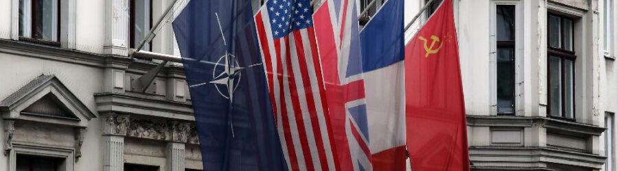 Die Flagge der Nato und Länderflaggen am ehemaligen Kontrollpunkt Checkpoint Charlie in Berlin.