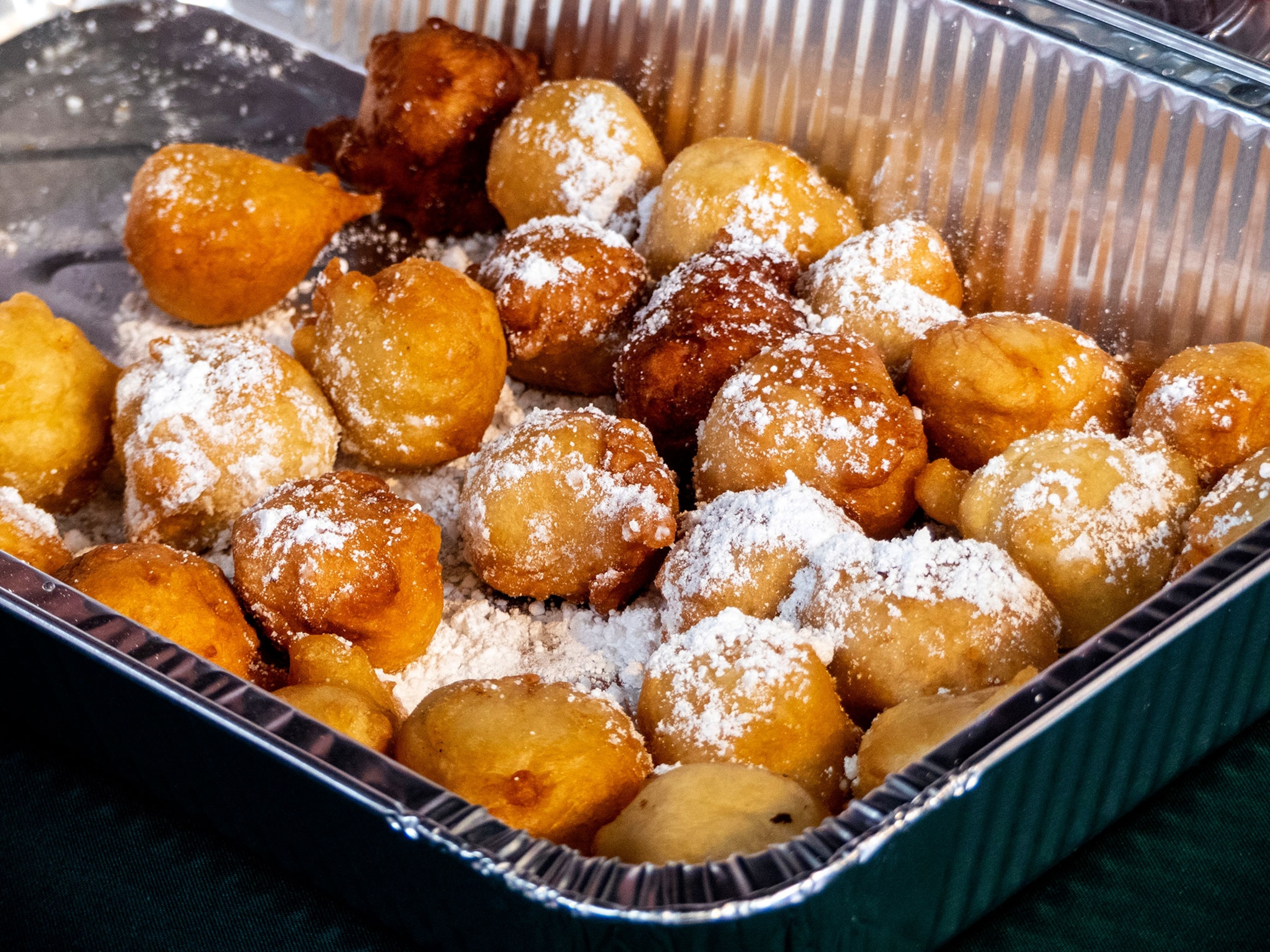 A tray of fried dough with a dusting of powdered sugar.