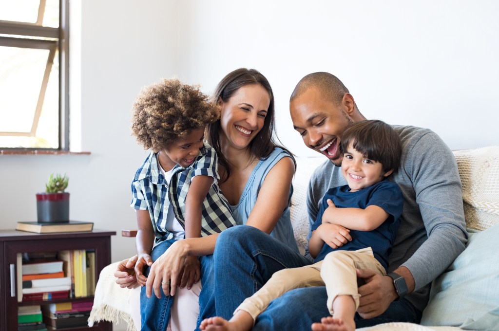 Happy multiethnic family laughing on a couch.