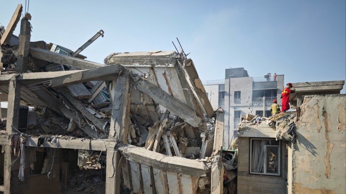 People look over damage to buildings following Israeli air strikes