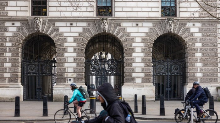 Commuters pass the Treasury government buildings in London